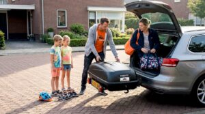 Een gezin gaat op pad met een Hapro trekhaakkoffer achter hun auto.